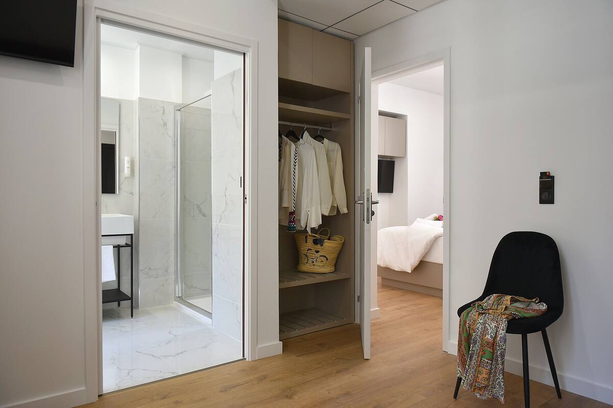 A modern bedroom with a bed, a chair, and a walk-in closet.