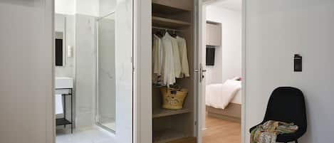 A modern bedroom with a bed, a chair, and a walk-in closet.