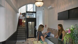 Ein Empfangsbereich mit einer Rezeption, einer Treppe und einem großen Fenster.
