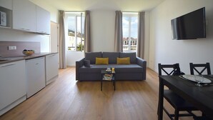 Eine moderne Wohnung mit grauem Sofa, Esstisch und Küchenzeile.