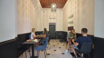 A dining area with black cushioned booths, a patterned floor, and a hanging light fixture.