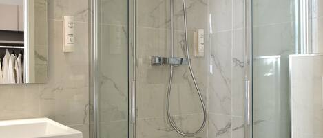 A modern bathroom with a glass-enclosed shower, a white sink, and a toilet.