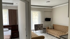 A modern hotel room with a bed, a sofa, a TV, and a desk. - Sidelya Apart (Gökçeada)