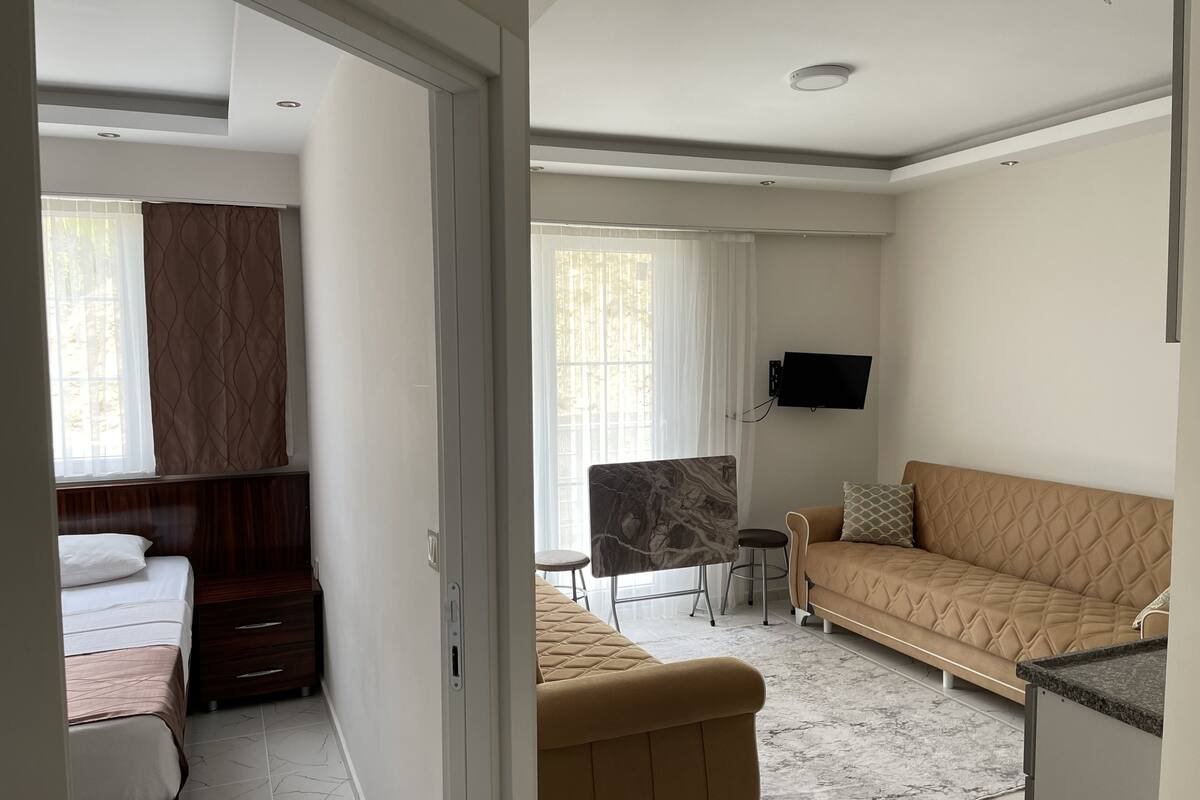 Una habitación de hotel moderna con cama, sofá, televisión y escritorio.