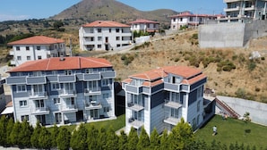 A residential area with modern multi-story buildings, a hillside, and a clear sky. - Sidelya Apart (Gökçeada)