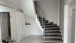 A modern staircase with a metal railing, white cabinets, and a clean, tiled floor. - Sidelya Apart (Gökçeada)