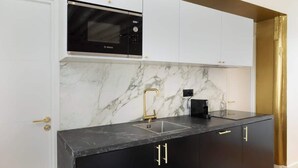 A modern kitchen with a black and white color scheme, featuring a Bosch microwave, a gold faucet, and black cabinets. - A Breathtaking  2BR/2BA in Le Marais (Paris)