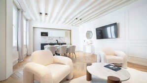 A spacious living area with a modern design, featuring a herringbone floor pattern, a large round coffee table, and comfortable seating. - A Breathtaking  2BR/2BA in Le Marais (Paris)