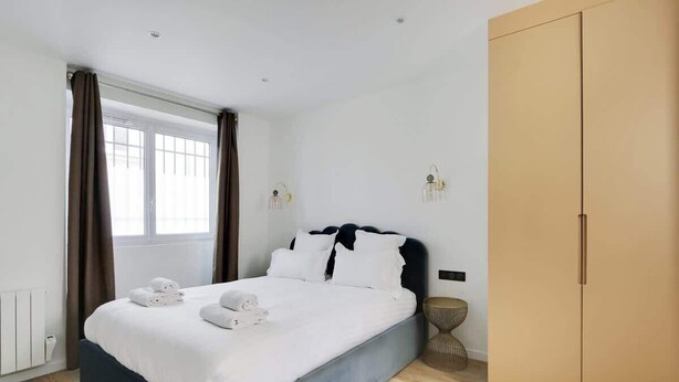 A modern hotel room with a bed, a wardrobe, and a window with curtains. - A Chic 1-BR in Sentier - Montorgueil (Paris)