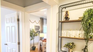 A hallway with a door, a mirror with shelves, and a 'HELLO' sign.