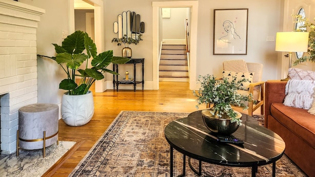 A living room with a fireplace, a round coffee table, a sofa, and a staircase leading to another room.