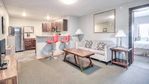Ein modernes Hotelzimmer mit einer Küchenzeile, einem Sofa, einem Couchtisch und einem kleinen Beistelltisch.