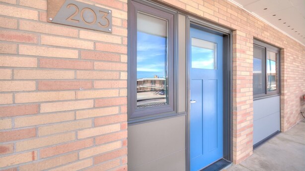 A brick building with a blue door and a number plate indicating the address 203. - 1BR with 2 beds and a kitchen on the 2nd floor (Rapid City)