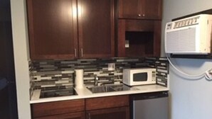 A kitchen with dark wooden cabinets, a white microwave, and a dishwasher.