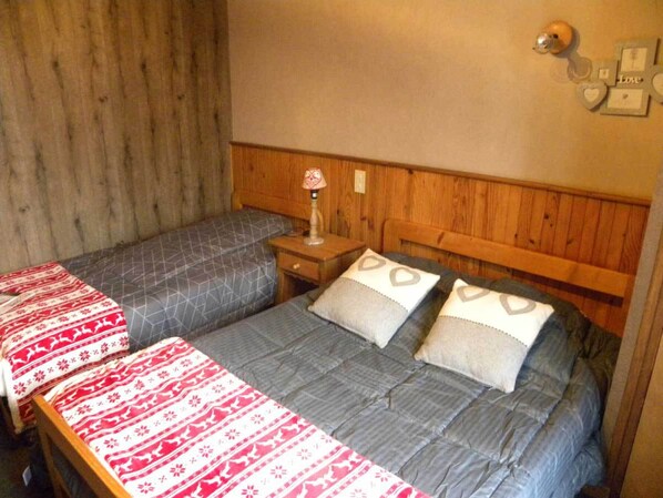 A room with two beds, each with patterned bedding, wooden headboards, and a nightstand with a lamp.