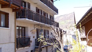 Ein mehrstöckiges Gebäude mit Balkonen, einem Schild, das ein Restaurant anzeigt, und Blick auf eine gebirgige Landschaft.