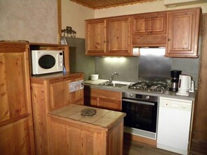A compact kitchen with wooden cabinets, a microwave, a sink, a stove, and a dishwasher.