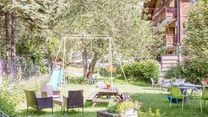 Ein Garten mit Schaukel, Gartenmöbeln und Rutsche.
