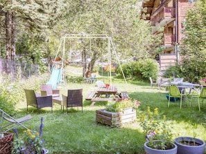 Ein Garten mit Schaukel, Gartenmöbeln und Rutsche.
