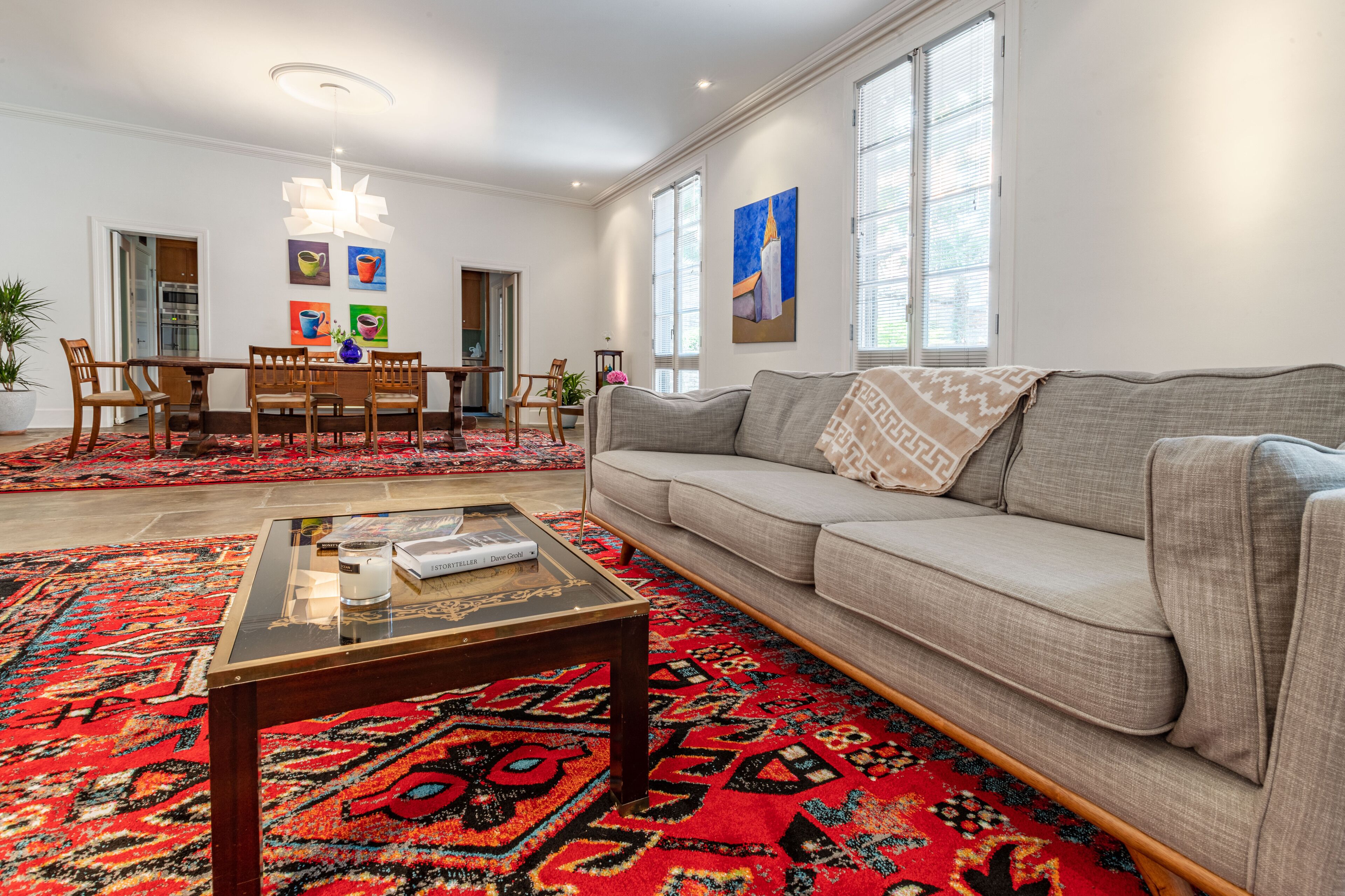 A living room with a sofa, coffee table, and a dining area with chairs and a table.