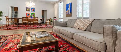 A living room with a sofa, coffee table, and a dining area with chairs and a table.