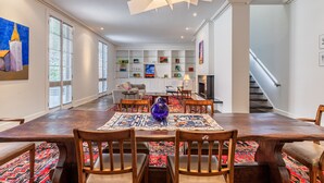 Un comedor amplio con una gran mesa de madera, varias sillas y una alfombra colorida con diseño.