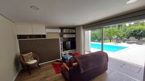 Una sala de estar moderna con un ventanal grande, una piscina y un rincón de descanso acogedor.