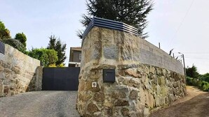 Un muro de piedra con una reja de metal y un camino pavimentado.