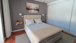 Un dormitorio con cama, mesita de noche, lámpara de pared, un cuadro y un armario.
