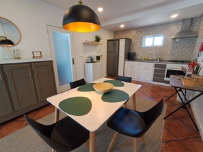 Uma cozinha moderna com uma mesa de jantar, cadeiras e uma luminária pendente.