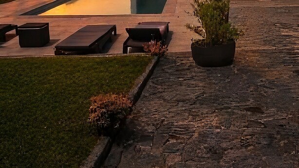 Una casa moderna con piscina, mobiliario exterior y vistas al atardecer.