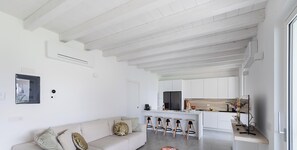 Ein modernes Interieur mit einer Couch, Barhocker, einer Küchenzeile und einem Esstisch.