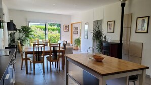 Une cuisine moderne avec un coin repas, de grandes fenêtres et des plantes en pot.