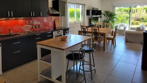 Une cuisine moderne avec des meubles noirs, un pare-feu rouge et un coin repas comprenant une table et des chaises en bois.