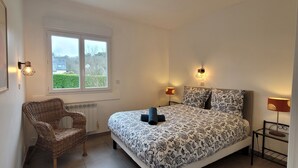 Une chambre à coucher avec un lit, deux lampes de chevet, une chaise, une fenêtre et un radiateur.