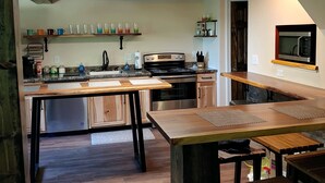 Een moderne keuken met een centraal eiland, ingebouwde apparatuur en een magnetron aan de muur.