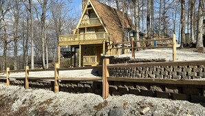 Een rustieke houten hut met stenen fundering, houten balkon en rieten dak.