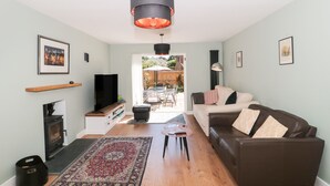 A living room with a fireplace, a sofa, a coffee table, and a rug. - 1 Charlotte Close (Poole)