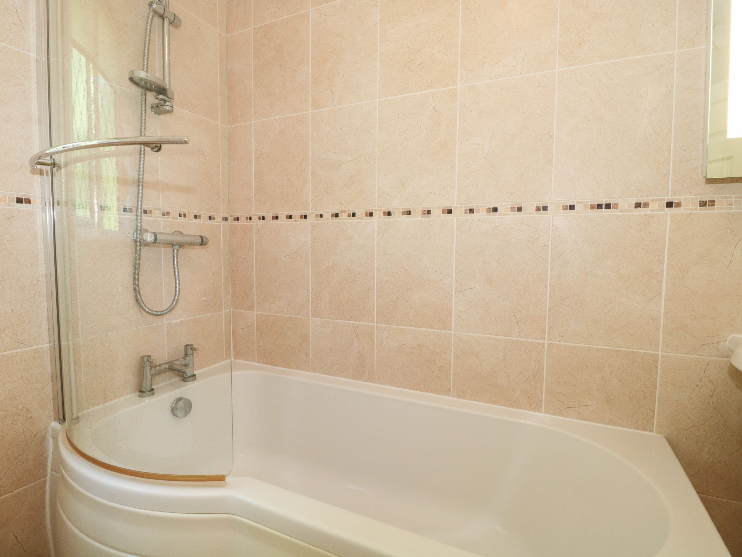 Une salle de bain équipée d’une baignoire, d’une douche et d’un espace de douche séparé par des parois en verre.