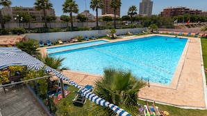 A rectangular pool with two separate sections, surrounded by palm trees and lounge chairs. - Stunning Ocean View! Communal Pool and Quick Walk to the Beach (Portimão)