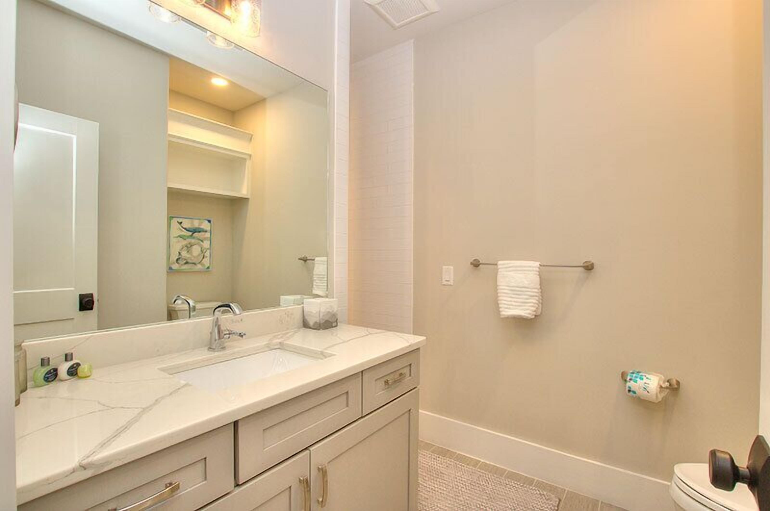 A bathroom with a large mirror, a sink, and a toilet.