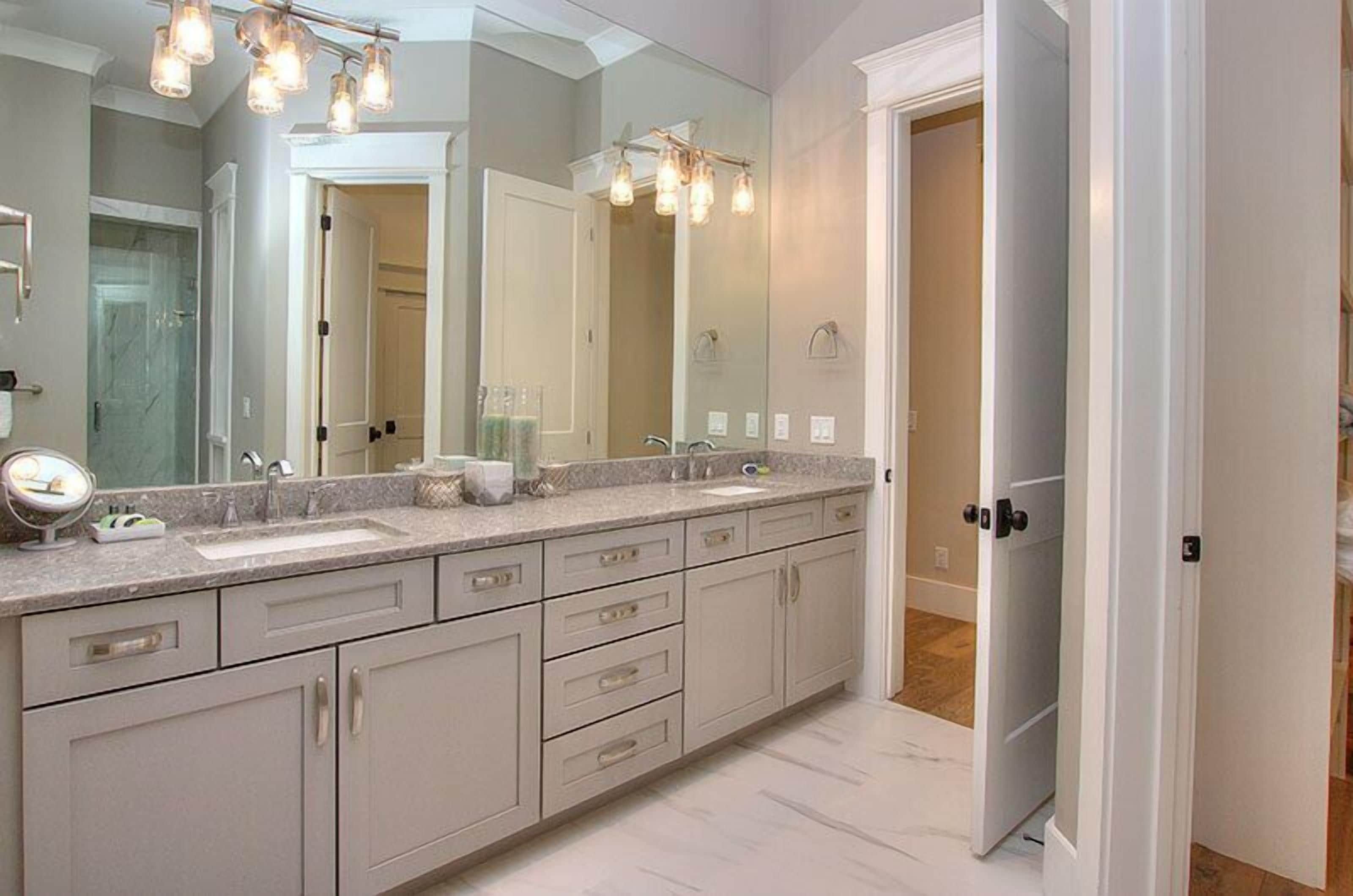 A spacious bathroom with a large vanity, a double sink, and a large mirror.