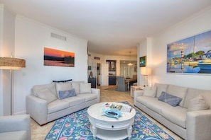 A living room with two sofas, a coffee table, and a colorful rug.