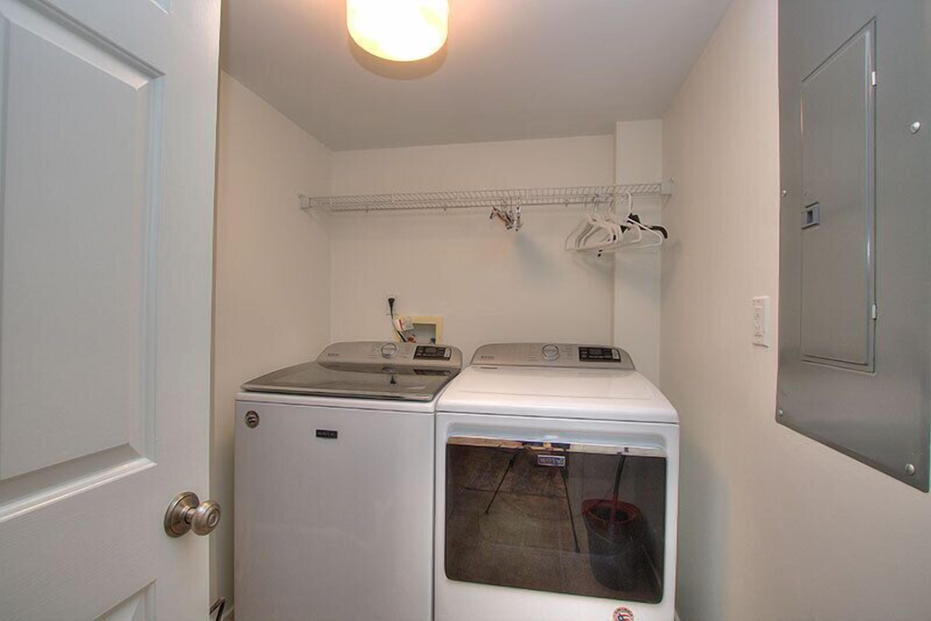 A laundry room with two washing machines and a drying rack.