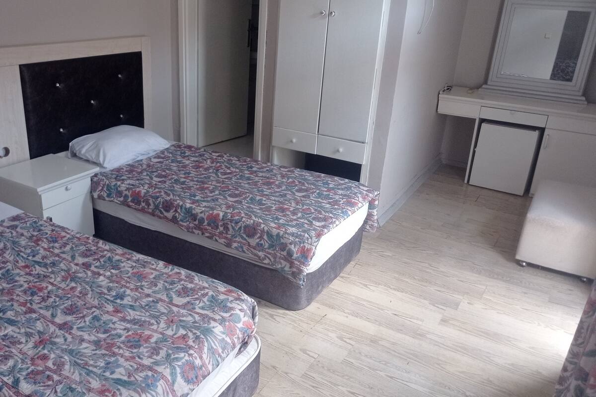 Habitación de hotel con dos camas, un armario, un escritorio pequeño y un espejo.