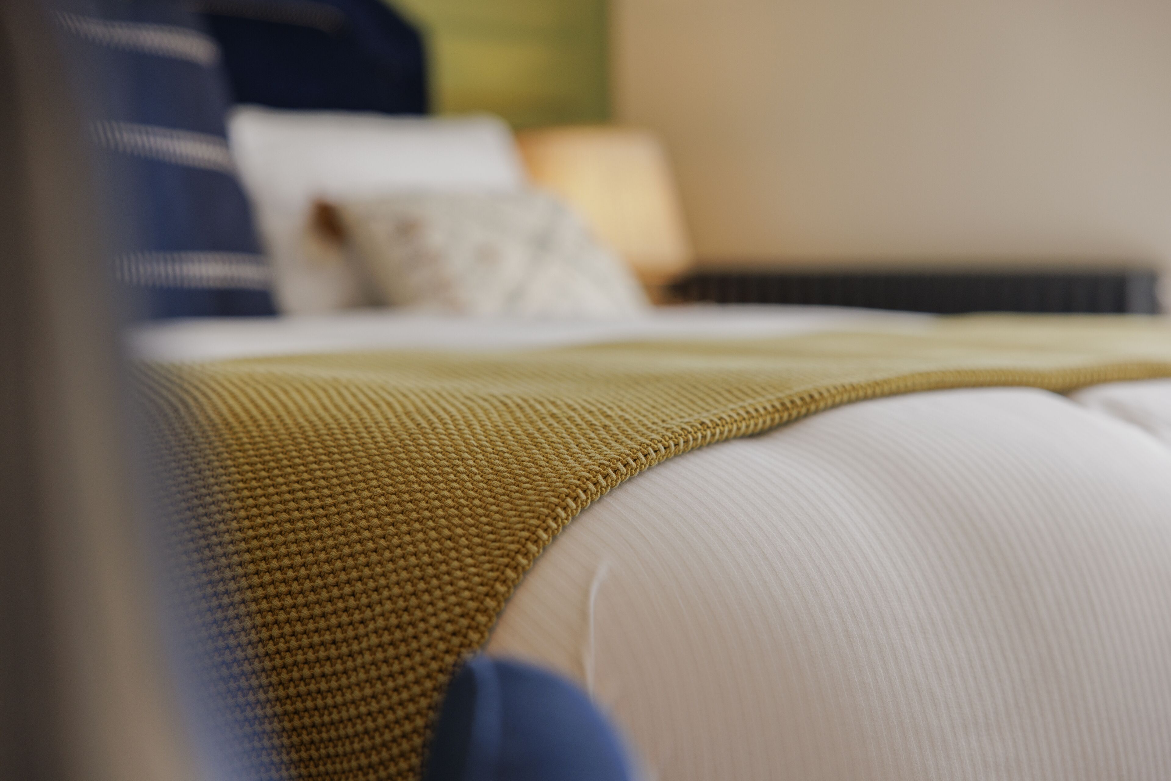 Uma cama com um cobertor amarelo e almofadas brancas.