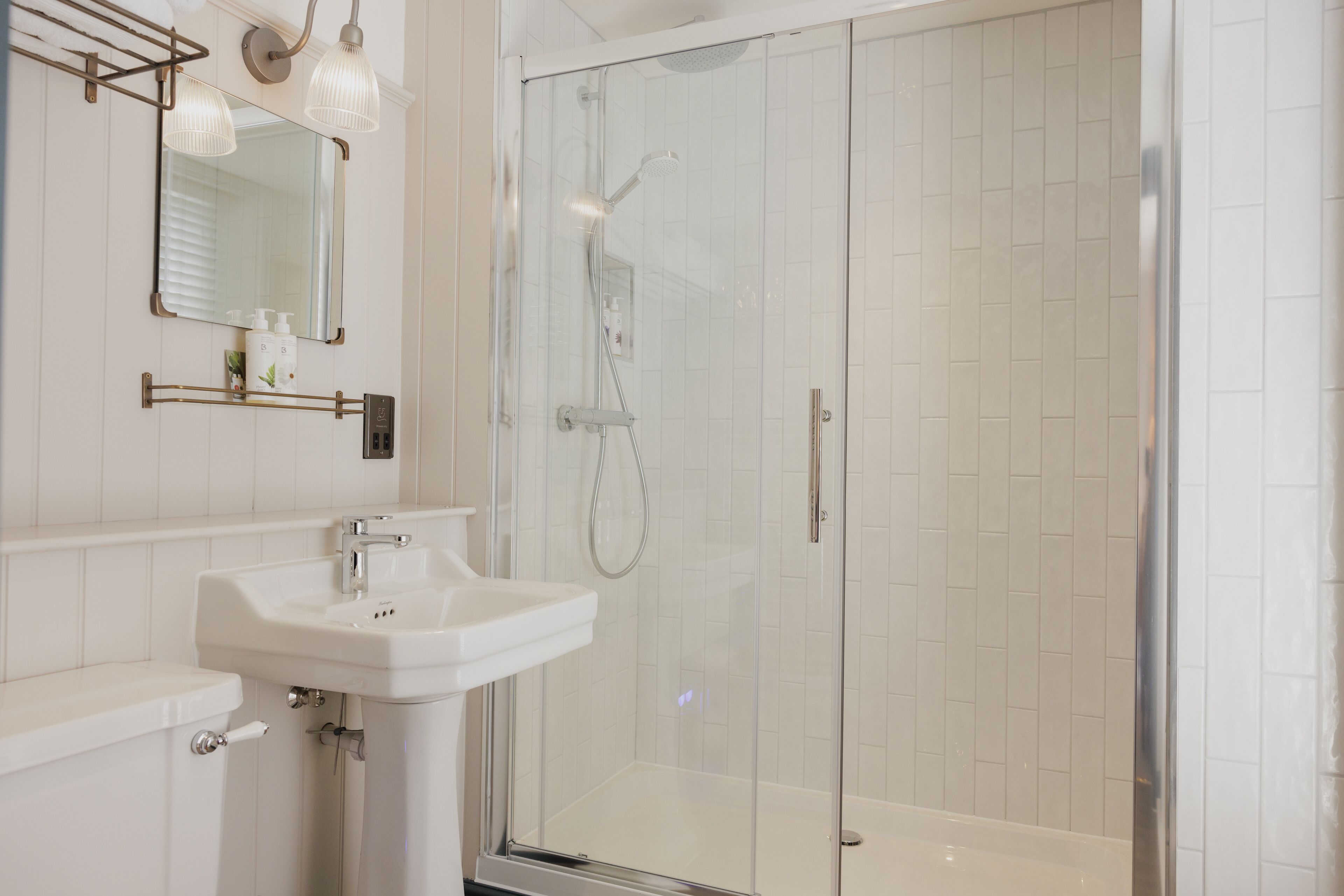 A modern bathroom with a glass-enclosed shower, a white sink, and a mirror above it.