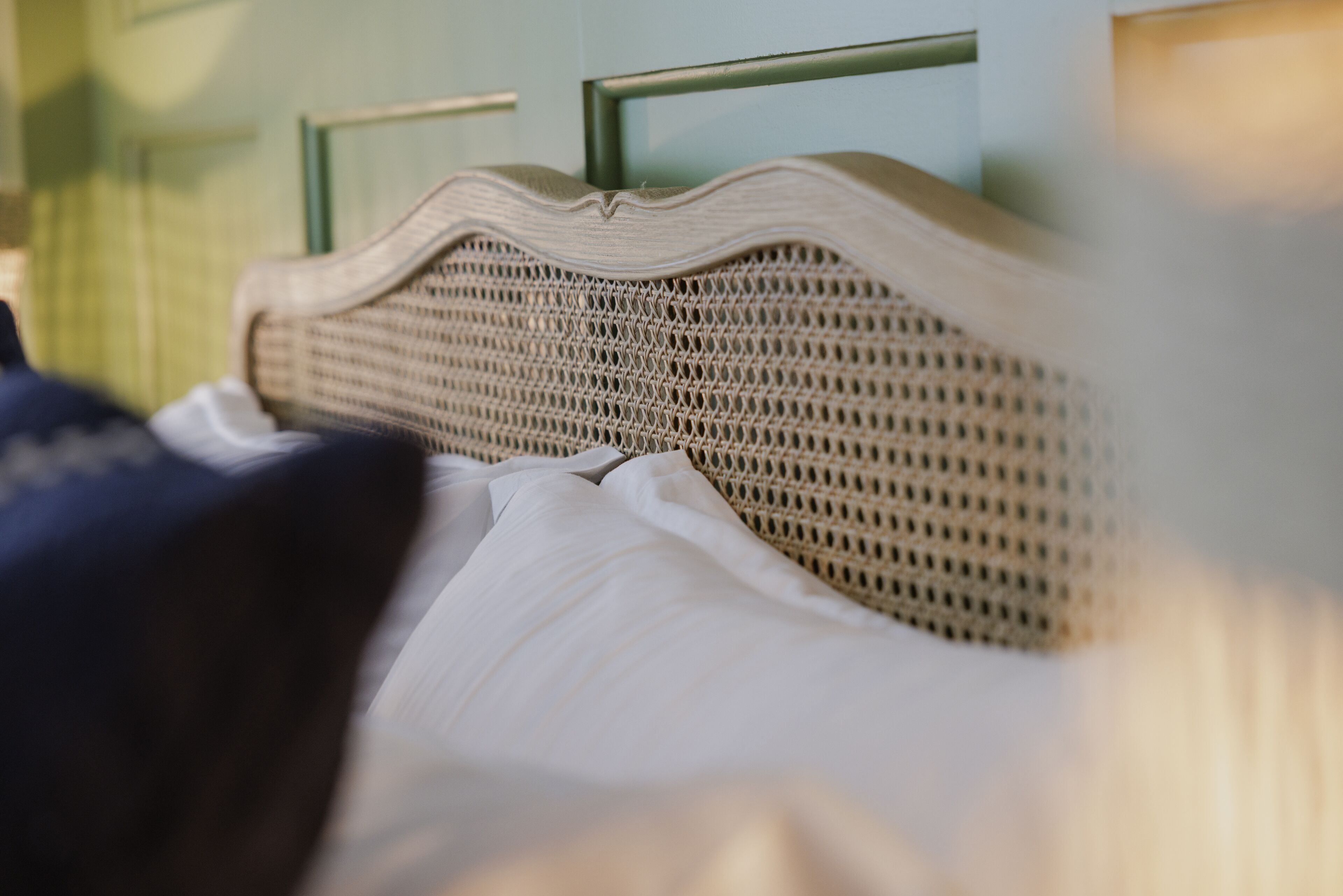 Un lit avec une tête de lit en osier et du linge de lit blanc.