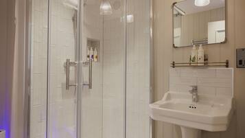 A modern bathroom with a glass-enclosed shower, a white sink, and a mirror above it.