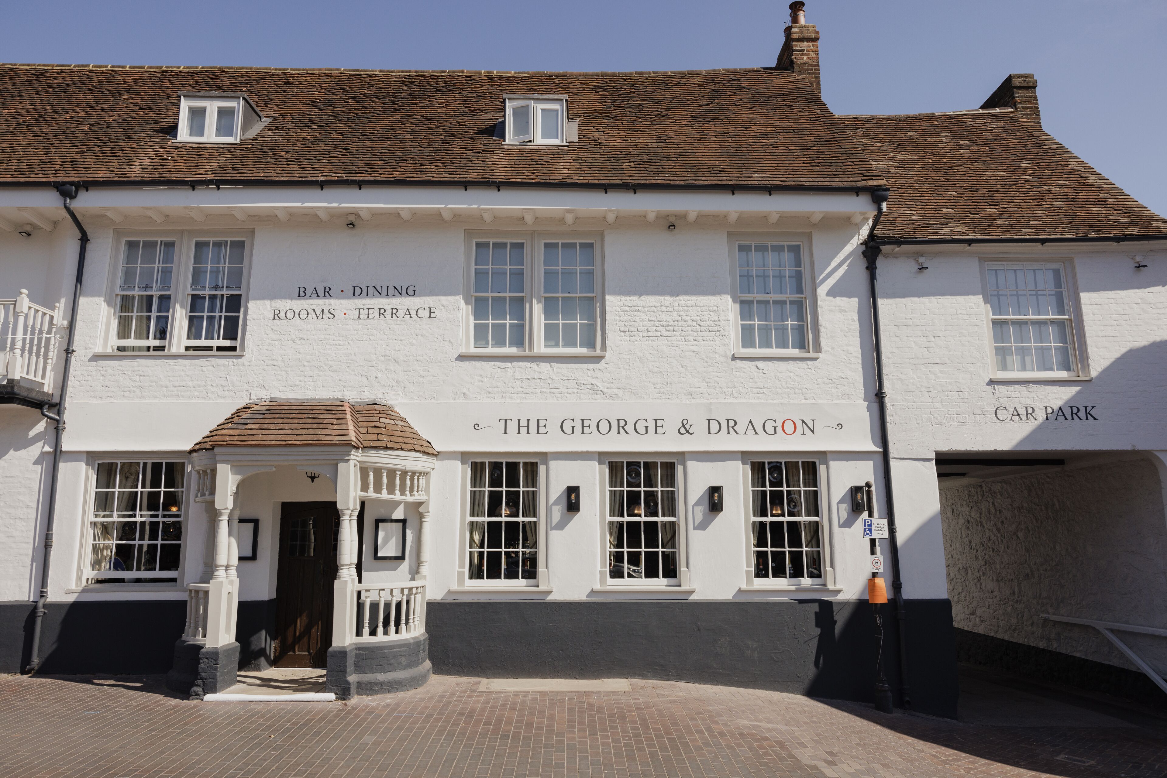 Un edificio blanco con un letrero que dice "The George & Dragon" y "Bar, Dining, Rooms, Terrace".